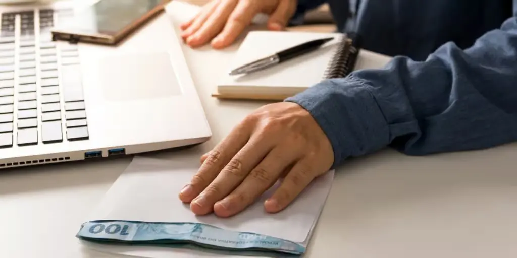 Assinatura de nota promissória sobre mesa de trabalho, representando formalização de dívida por meio de título de crédito.