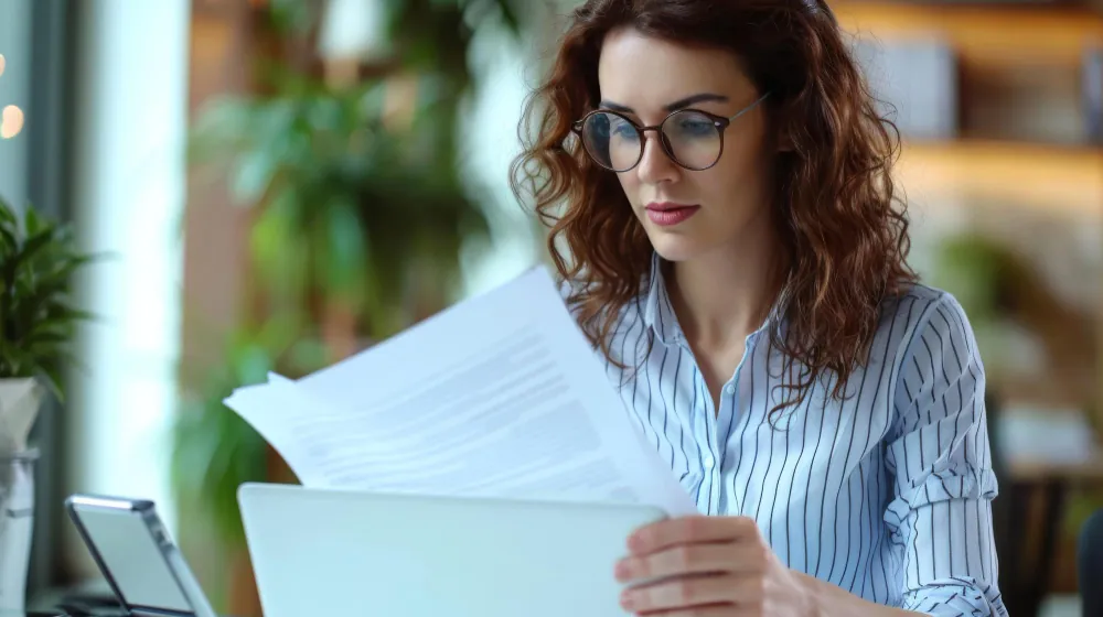 Profissional analisando documentos financeiros no computador em contexto de risco sacado empresarial