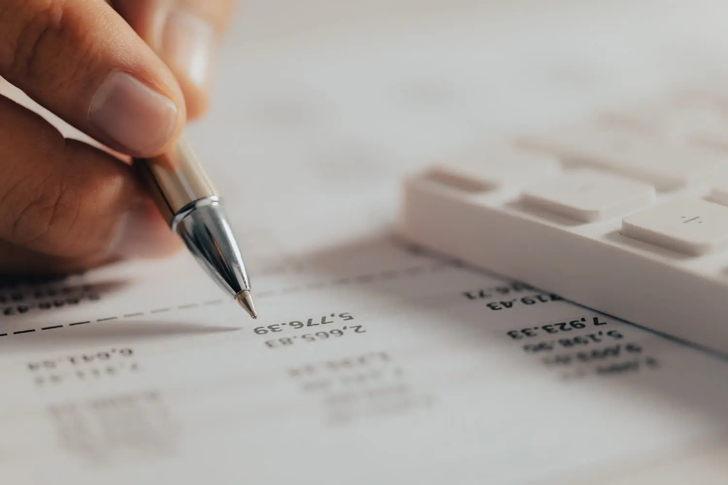 Profissional usando calculadora com lastros financeiros sobre a mesa